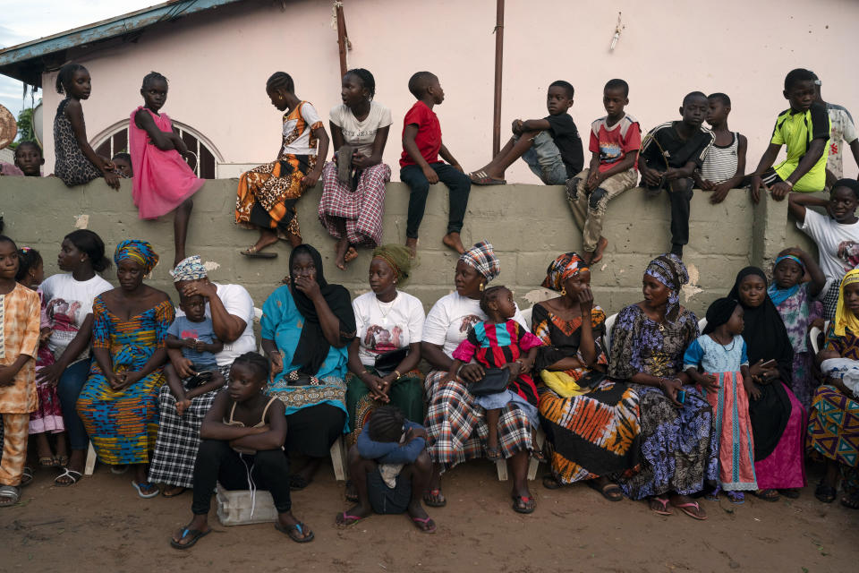 Neighbors, friends and relatives of boys who are taking part in the initiation rites, attend a Kankurang ceremony in Bakau, Gambia, Saturday, Oct. 2, 2021. The Kankurang rite was recognized in 2005 by UNESCO, which proclaimed it a cultural heritage. Despite his fearsome appearance, the Kankurang symbolizes the spirit that provides order and justice and is considered a protector against evil. He appears at ceremonies where circumcised boys are taught cultural practices, including discipline and respect. (AP Photo/Leo Correa)