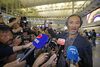 Chinese dissident writer Ma Jian shows his passport to media after arriving Hong Kong international airport, Friday, Nov. 9, 2018. Hong Kong on Friday permitted dissident writer Ma to enter to attend a literary festival, even after an arts venue in the city canceled his appearance. Ma, whose novels frequently satirize China's communist leaders, told reporters he experienced nothing unusual while passing through passport control and that organizers were still lining-up a place for him to speak. "The lecture will definitely happen. If there is a single Hong Kong person who is willing to listen, or a single reader who contacts me, I will be there," Ma said. (AP Photo/Kin Cheung)