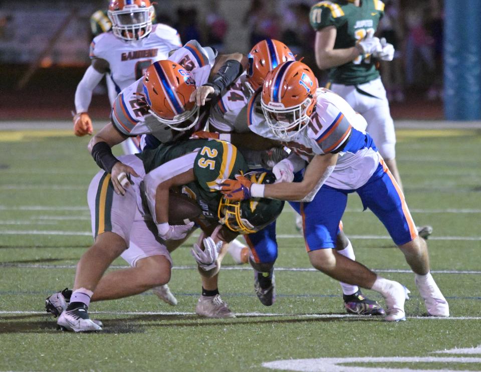 The Palm Beach Gardens defense swarms a Jupiter ball carrier in the Gators' district championship win over the Warriors on Friday, Oct. 28, 2022 in Jupiter.