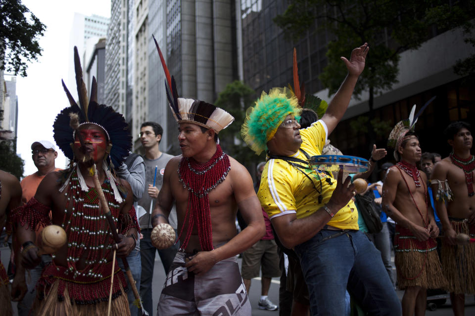 Indians and a person with a tambourine protest during a march in Rio de Janeiro, Brazil, Monday, Nov. 26, 2012. Thousands of demonstrators gathered in downtown Rio de Janeiro for a march against legislation that officials here insist would strip this oil-producing state of much of its income from the energy sector. The protesters are calling on President Dilma Rousseff to veto the measure. (AP Photo/Victor R. Caivano)