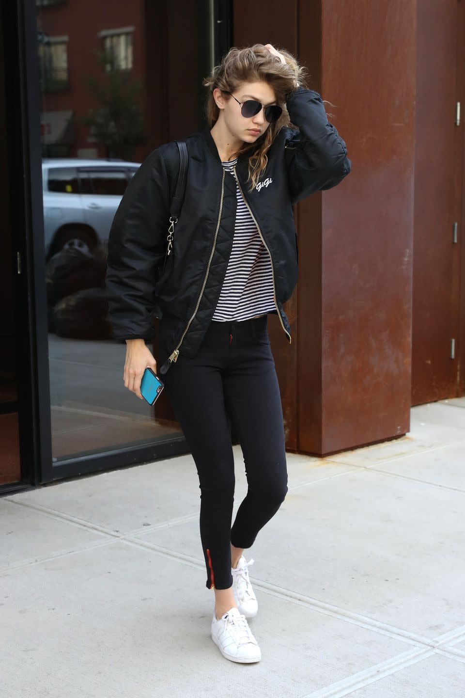<p>Hadid rocks her go-to athleisure look with a personalized black bomber jacket featuring a small "Gigi" logo on the chest</p>