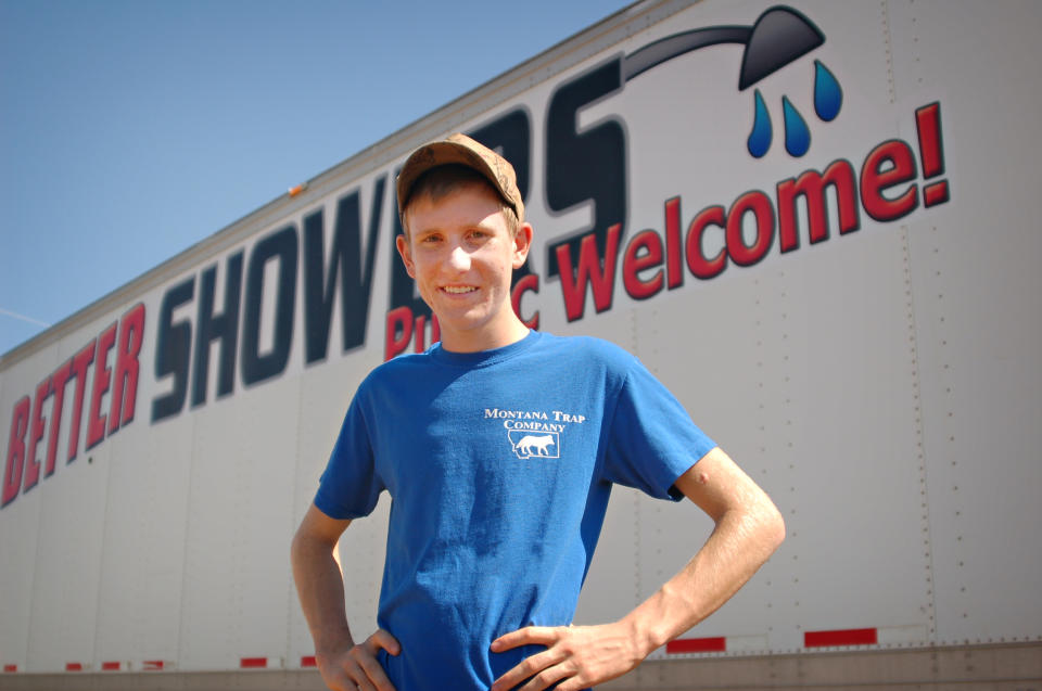 In this Thursday, Aug. 23, 2012 photo, Evan Jensen stands beside his mobile shower business, Better Showers, near Alexander, N.D. Jensen raised money for the facility, which caters largely to workers in North Dakota's oil patch, by trapping muskrats and hopes profits from the business will pay for his college tuition. (AP Photo/James MacPherson)