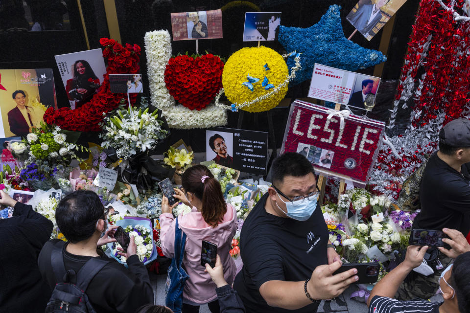 Fans lay flowers and take photographs outside the Mandarin Oriental Hotel to commemorate the 20th anniversary of the passing of Canto-pop singer and actor Leslie Cheung in Hong Kong, Saturday, April 1, 2023. (AP Photo/Louise Delmotte)