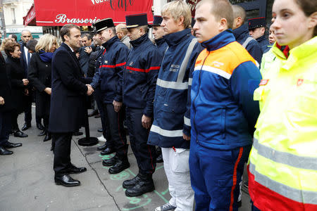 French President Emmanuel Macron (2ndL) and and his wife Brigitte Macron (L) greet first-aid workers as they stand in front of the 'Comptoir Voltaire' bar during a ceremony marking the second anniversary of the Paris attacks of November 2015 in which 130 people were killed, in Paris, France, November 13, 2017. REUTERS/Etienne Laurent/Pool