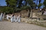 Greek actress Xanthi Georgiou, left, playing the role of the High Priestess, holds the torch as police officers, right, run to detain pro-democracy protesters at the lighting of the Olympic flame at Ancient Olympia site, birthplace of the ancient Olympics in southwestern Greece, Monday, Oct. 18, 2021. The flame will be transported by torch relay to Beijing, China, which will host the Feb. 4-20, 2022 Winter Olympics. (AP Photo/Thanassis Stavrakis)