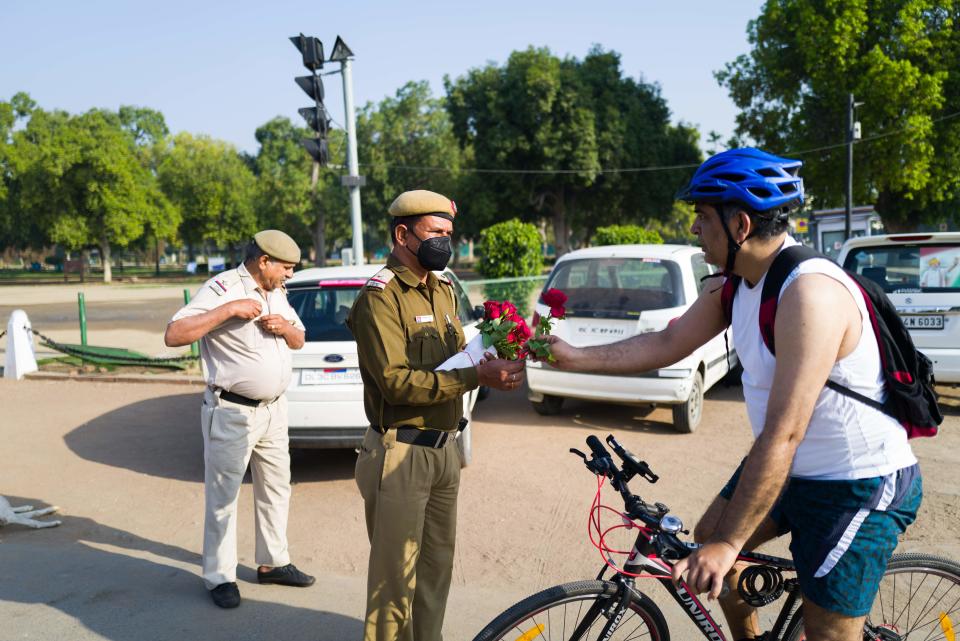 A policeman gives a rose to a cyclist in a bid to inspire him to stay home during a one-day Janata (civil) curfew imposed as a preventive measure against the COVID-19 coronavirus in New Delhi on March 22, 2020. - Nearly one billion people around the world were confined to their homes, as the coronavirus death toll crossed 13,000 and factories were shut in worst-hit Italy after another single-day fatalities record. (Photo by Jewel SAMAD / AFP) (Photo by JEWEL SAMAD/AFP via Getty Images)