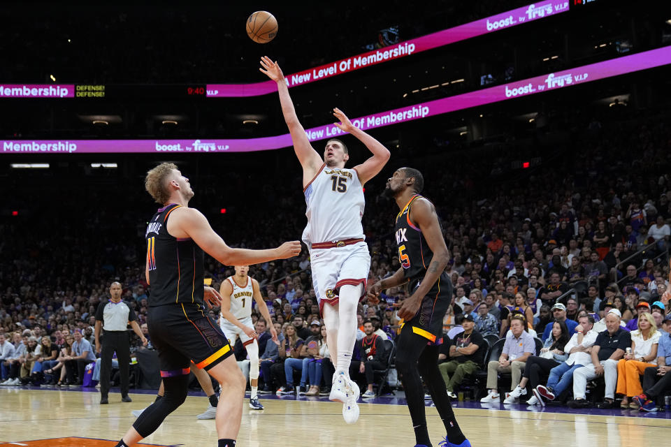 Denver Nuggets center Nikola Jokic (15) shoots as Phoenix Suns center Jock Landale and forward Kevin Durant, right, look on during the second half of Game 3 of an NBA basketball Western Conference semifinal game, Friday, May 5, 2023, in Phoenix. The Suns defeated the Nuggets 121-114. (AP Photo/Matt York)