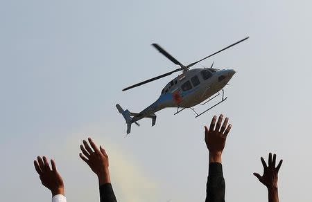 Supporters wave towards a helicopter carrying Keshav Prasad Maurya, the Uttar Pradesh state's president for the ruling Bharatiya Janata Party (BJP), during an election campaign rally in Bah in Uttar Pradesh, India, February 2, 2017. REUTERS/Adnan Abidi