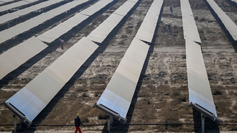 A worker walks past rows of solar panels at the Khavda Renewable Energy Park.  - Punit Paranjpe/AFP/Getty Images