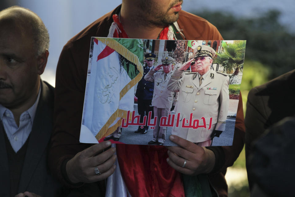 People attend the funeral of late Algerian military chief Gaid Saleh in Algiers, Algeria, Wednesday, Dec. 25, 2019. Banner in Arabic reads "May God have his mercy on you, hero". Algeria is holding an elaborate military funeral for the general who was the de facto ruler of the gas-rich country amid political turmoil throughout this year. (AP Photo/Fateh Guidoum)