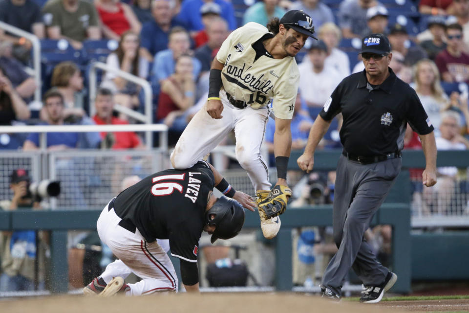 Louisville's Justin Lavey (16) steals third base as Vanderbilt third baseman Austin Martin, top, leaps in an attempt to catch the throw during the seventh inning of an NCAA College World Series baseball game in Omaha, Neb., Friday, June 21, 2019. Lavey went on to score on the throwing error. (AP Photo/Nati Harnik)