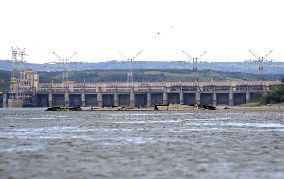 The wreckage of a WWII German warship is seen in front of Djerdap II, a large dam on the Danube River, between Romania and Serbia, near Prahovo, Serbia, Monday, Aug. 29, 2022. The worst drought in Europe in decades has not only scorched farmland and hampered river traffic, it also has exposed a part of World War II history that had almost been forgotten. The hulks of dozens of German battleships have emerged from the mighty Danube River as its water levels dropped. (AP Photo/Darko Vojinovic)