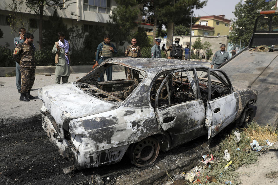 Security personnel inspect a damaged vehicle that was firing rockets in Kabul, Afghanistan, Tuesday, July 20, 2021. At least three rockets hit near the presidential palace on Tuesday shortly before Afghan President Ashraf Ghani was to give an address to mark the Muslim holiday of Eid-al-Adha. (AP Photo/Rahmat Gul)