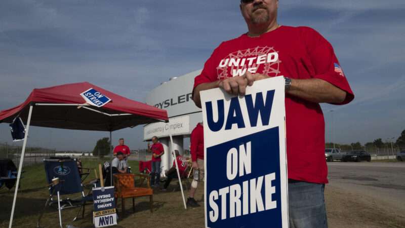A man holding a sign that reads "UAW ON STRIKE"