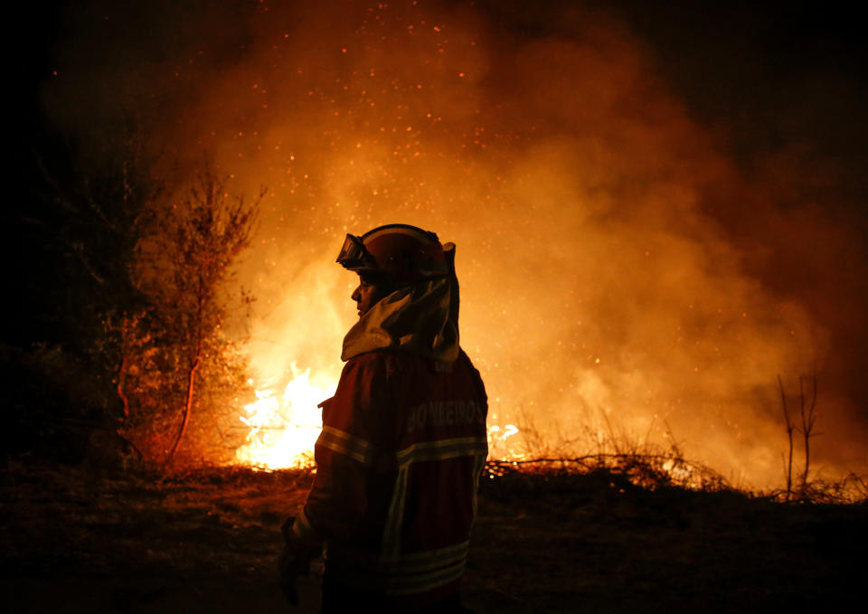 A firefighter&nbsp;stands&nbsp;silhouetted against&nbsp;the flames in Cabanoes near Lousa, Portugal, on Oct. 16, 2017. (Photo: Pedro Nunes / Reuters)