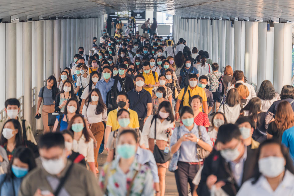 crowds of Asian people wearing face protection while going to their workplace in Bangkok at morning rush hour. wear medical face mask to protect from infection of viruses, pandemic, outbreak and epidemic of disease in crowded