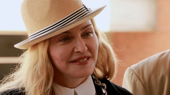 US pop diva Madonna looks on during the inspection of a 50-bed surgical unit for children that her charity, Raising Malawi, is funding at Queens Elizabeth hospital in the commercial capital Blantyre on July 10, 2016. She wears a straw hat with black and white band and her blonde hair is loose.