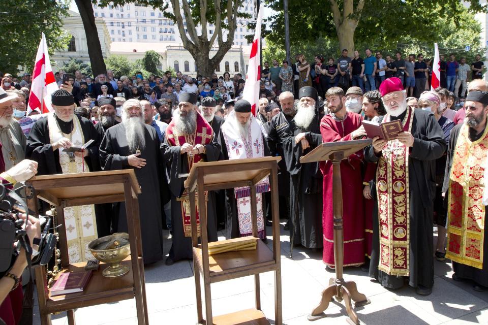 Georgian Orthodox priests, opponents of the march, pray as they block off the capital's main avenue to an LGBT march in Tbilisi, Georgia, Monday, July 5, 2021. A protest against a planned LGBT march in the Georgian capital turned violent on Monday as demonstrators attacked journalists. Organizers of the Tbilisi March For Dignity that was to take place in the evening cancelled the event, saying authorities had not provided adequate security guarantees. (AP Photo/Shakh Aivazov)