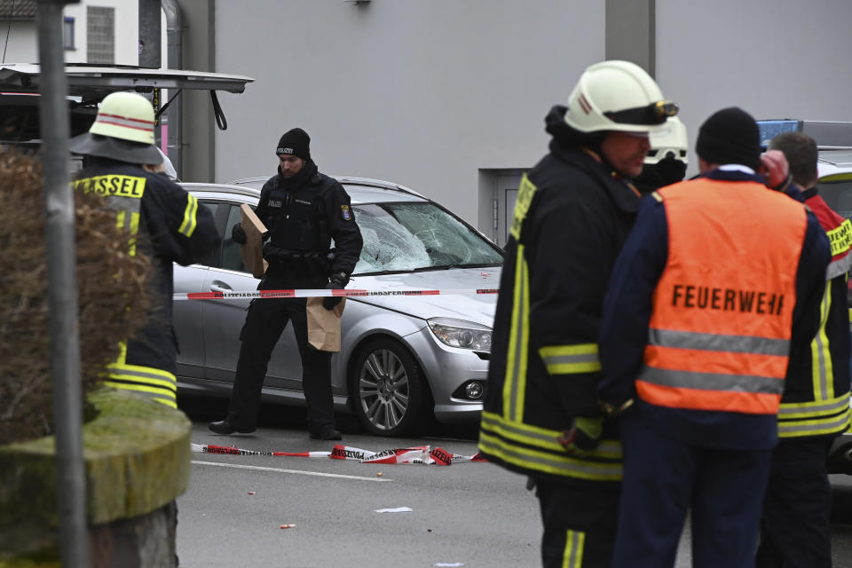 Police and rescue workers stand next to the scene of the accident with a car that is said to have crashed into a carnival parade in Volkmarsen, central Germany, Monday, Feb. 24, 2020. Several people have been injured, according to the police. The driver had been arrested by the police. (Uwe Zucchi/dpa via AP)