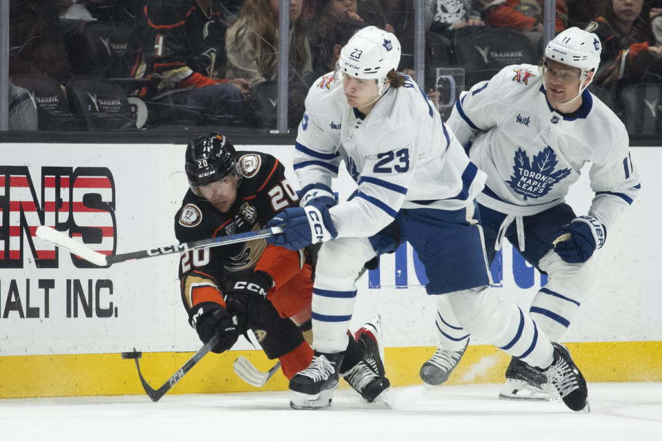 Anaheim Ducks right wing Brett Leason (20) clears the puck away from Toronto Maple Leafs left wing Matthew Knies (23) during the first period of an NHL hockey game Wednesday, Jan. 3, 2024, in Anaheim, Calif. (AP Photo/Kyusung Gong)