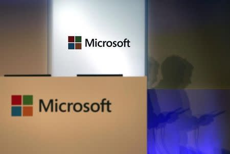 A shadow of a man using his mobile phone is cast near Microsoft logo at the 2014 Computex exhibition in Taipei June 4, 2014. REUTERS/Pichi Chuang