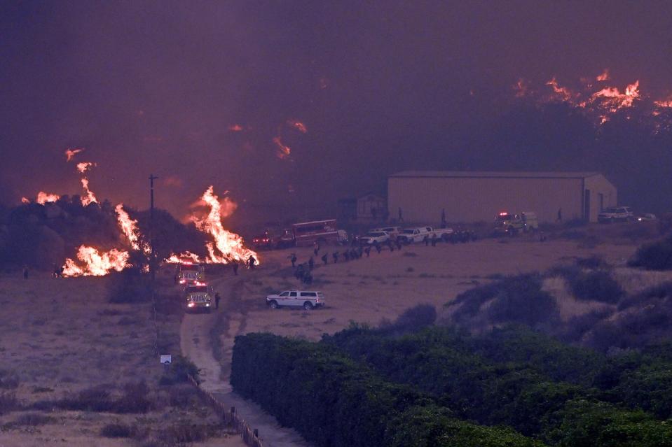 September 07: Firefighters protect a structure surrounded by fire at the top of Fairview Avenue during the Fairview fire in Hemet on Wednesday, Sept. 7, 2022.