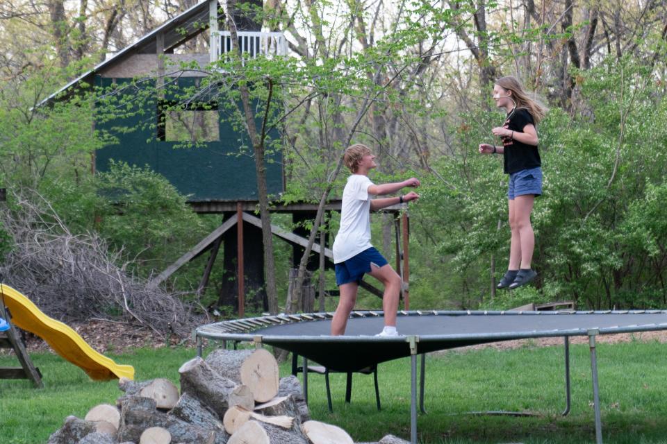 Wesley Budge, 15, helps to double-jump his sister, Norah, 12, on their trampoline Monday afternoon.