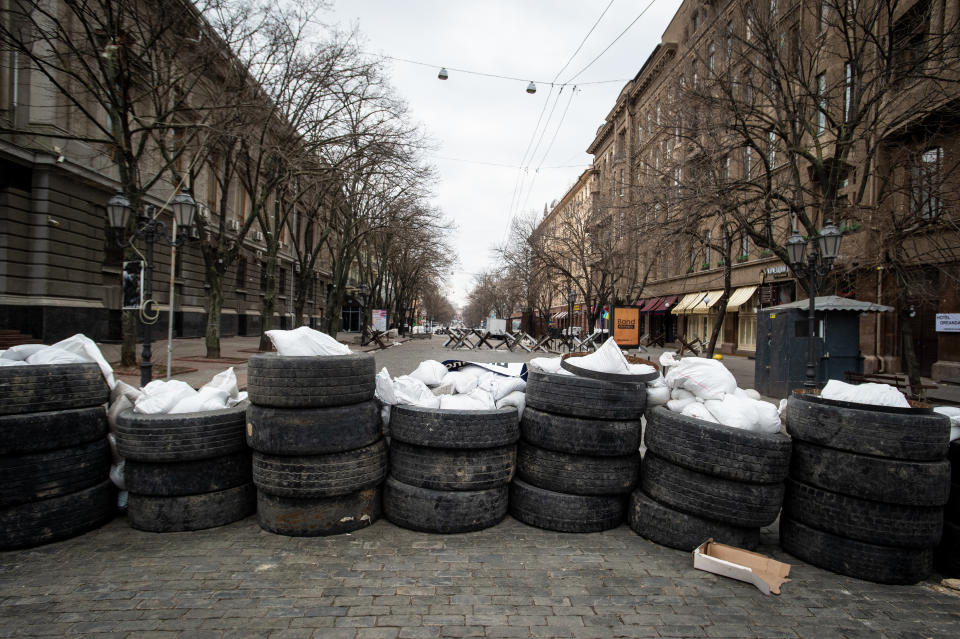 A wall of tires stacked three or four high blocks a road. 