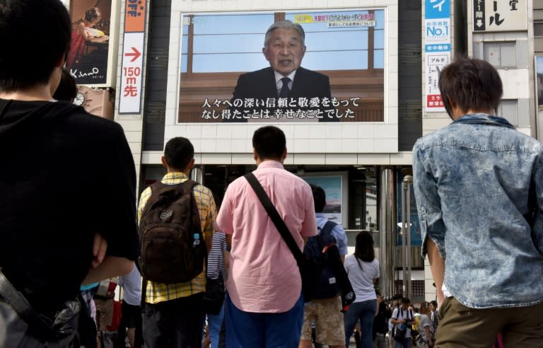 Japanese watch a big video screen on a Tokyo street as Emperor Akihito addresses the nation on August 8, 2016