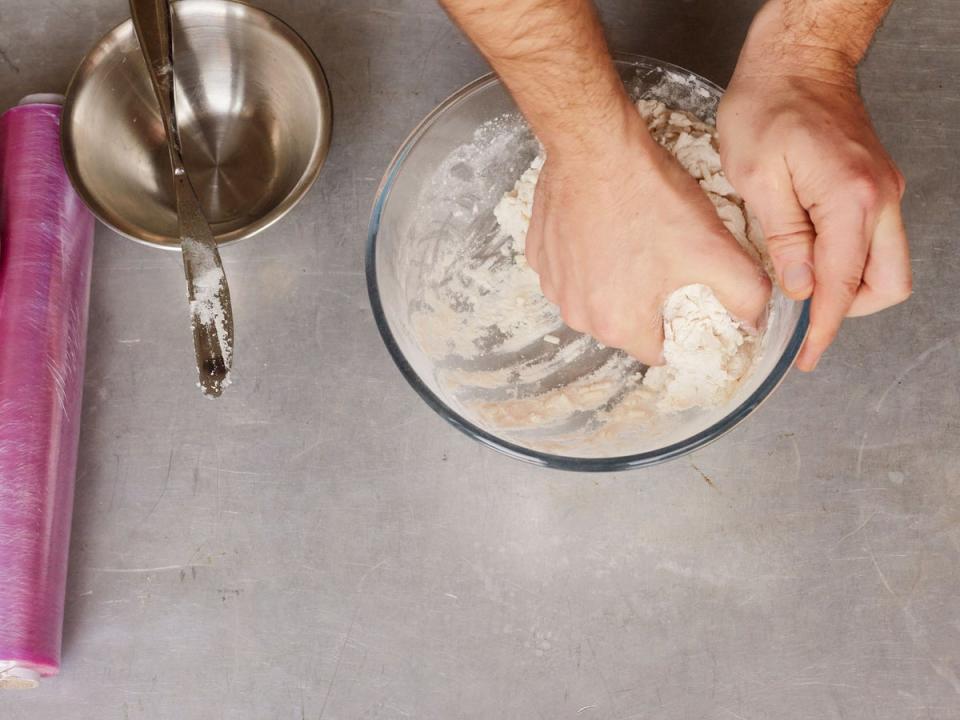 Gradually stir the water into the flour mix, eventually using one hand to pat together into a ball (Joe Woodhouse)