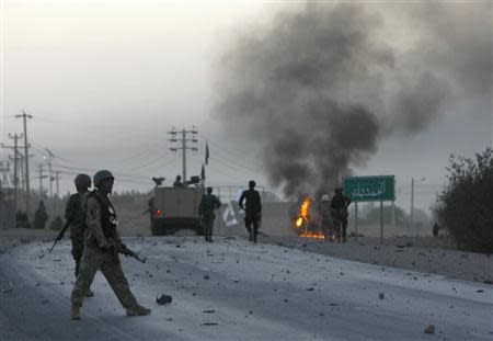 Afghan soldiers walk towards flames outside the U.S. Consulate after an attack by insurgents, in Herat province September 13, 2013. REUTERS/Mohammad Shoib