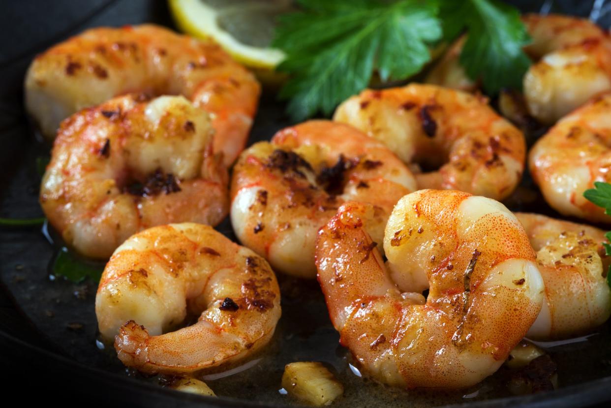 prawns shrimps roasted in a black pan with garlic, lemon, spices  and italian parsley garnish, close up, selected focus, narrow depth of field