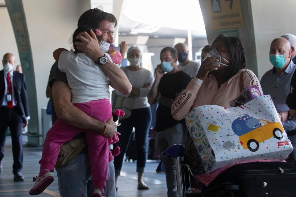 Sandro Manzato, from the Veneto region, hugs his daughter Yearline, 3, as she arrives with her mum Rubiela Perea, right, from Bogota, Colombia on June 3, 2020.