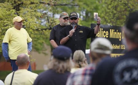 Joseph Rice of the Oath Keepers (R) holds a copy of the U.S. Constitution while speaking alongside Sugar Pine Mine owners George Backes (L) and Rick Barclay (C) at a rally outside the Bureau of Land Management's offices in Medford, Oregon April 23, 2015. REUTERS/Jim Urquhart