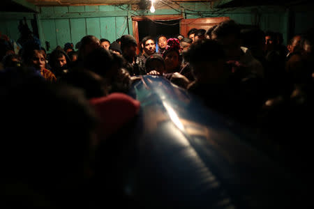 Family, friends and community members mourn around a coffin carrying the body of Misael Paiz, 25, at a wake inside his family home in Aguacate, Huehuetenango, Guatemala, October 28, 2018. REUTERS/Lucy Nicholson