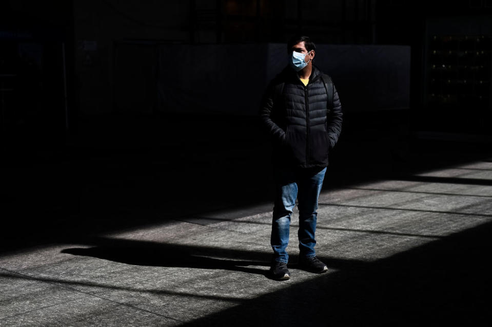 A man in a mask stands outside alone in Italy.