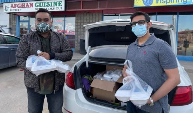 Haris Khan and Tahir Shaikh collect food from a local restaurant to deliver to people across Regina. Khan began the food drive in honour of his late father, who died from COVID-19, to help people during the holy month of Ramadan. (Janani Whitfield/CBC - image credit)