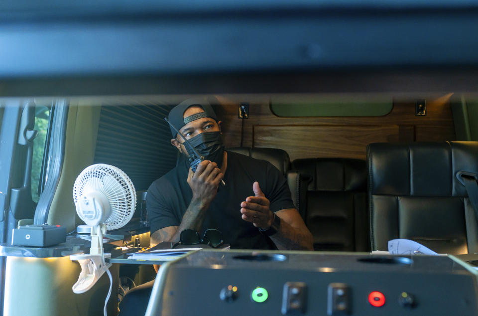 This image released by Netflix shows director Antoine Fuqua working from a vehicle on the set of "The Guilty." (Glen Wilson/Netflix via AP)