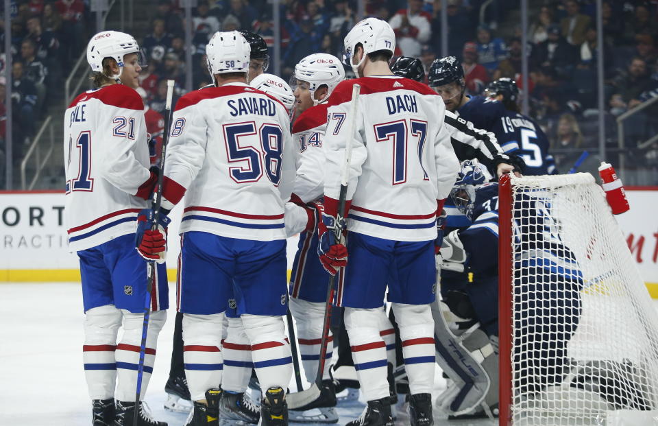 Montreal Canadiens' Nick Suzuki (14) and teammates celebrate a goal on Winnipeg Jets goaltender Connor Hellebuyck during the first period of an NHL hockey game Thursday, Nov. 3, 2022, in Winnipeg, Manitoba. (John Woods/The Canadian Press via AP)