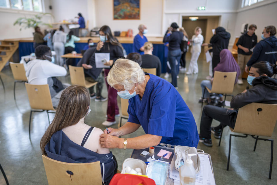 A student at Holtet high school receives the first dose of Pfizer vaccine against COVID-19 in the school's auditorium in Oslo, Tuesday, Sept. 7, 2021. Vaccination of teenagers has started some places in Norway. (Heiko Junge/NTB via AP)