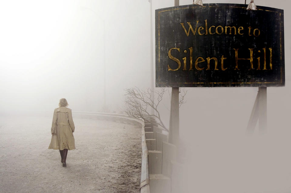 A woman walking along the side of the road and a sign that says, "Welcome to Silent Hill"