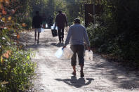 Migrants carry empty canisters to be filled with a water near the Vucijak refugee camp outside Bihac, northwestern Bosnia, Monday, Oct. 21, 2019. Authorities in the town of Bihac on Monday stopped the delivery of water supplies to the Vucjak camp saying they want to draw attention to the problems in the camp set up on a former landfill and near mine fields from the 1992-95 war. (AP Photo/Eldar Emric)