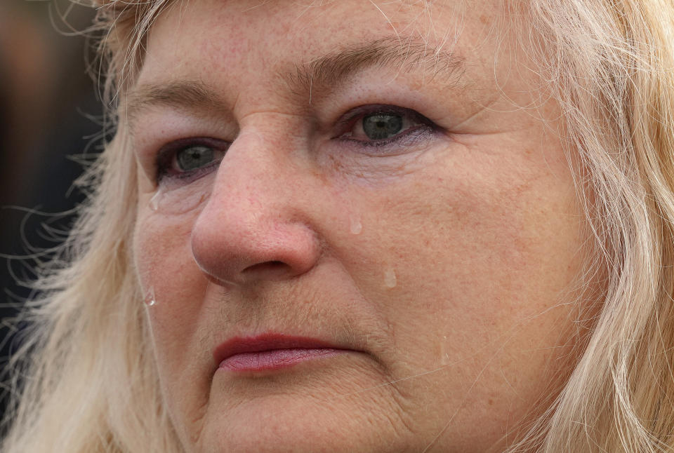 A woman cries during the singing of the national anthem during a visit by Ukrainian President Volodymyr Zelenskyy in Okhtyrka in the Sumy region of Ukraine, Tuesday March 28, 2023. (AP Photo/Efrem Lukatsky)