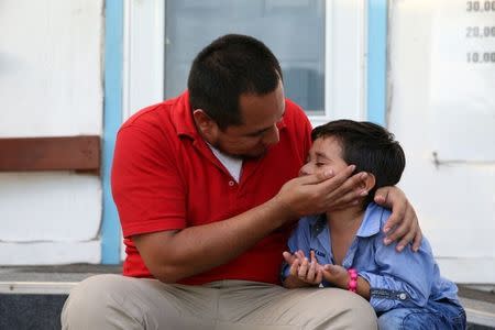 Walter Armando Jimenez Melendez, an asylum seeker from El Salvador, arrives with his four year-old son Jeremy at La Posada Providencia shelter in San Benito, Texas, U.S., shortly after he said they were reunited following separation since late May while in detention July 10, 2018. REUTERS/Loren Elliott