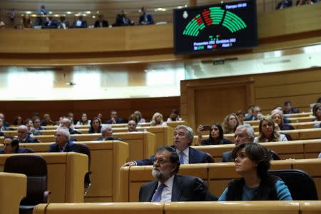 Spain's Prime Minister Mariano Rajoy (L) and Deputy Prime Minister Soraya Saenz de Santamaria look on as the results of a vote in the upper house Senate approving emergency measures to take control of the Catalan government are seen in a scoreboard in Madrid, Spain, October 27, 2017. REUTERS/Susana Vera