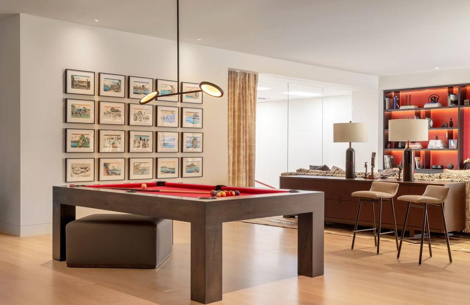 <p>In this billiard room designed by <a href="https://heatherhilliard.com/" rel="nofollow noopener" target="_blank" data-ylk="slk:Heather Hilliard;elm:context_link;itc:0;sec:content-canvas" class="link ">Heather Hilliard</a>, there's something for everyone to do. Whether it's hanging out on the sofa with a good book or for family movie night, playing squash (yes, that's a home squash court behind that glass in the corner), or playing pool, this is the ultimate hang out space. </p>