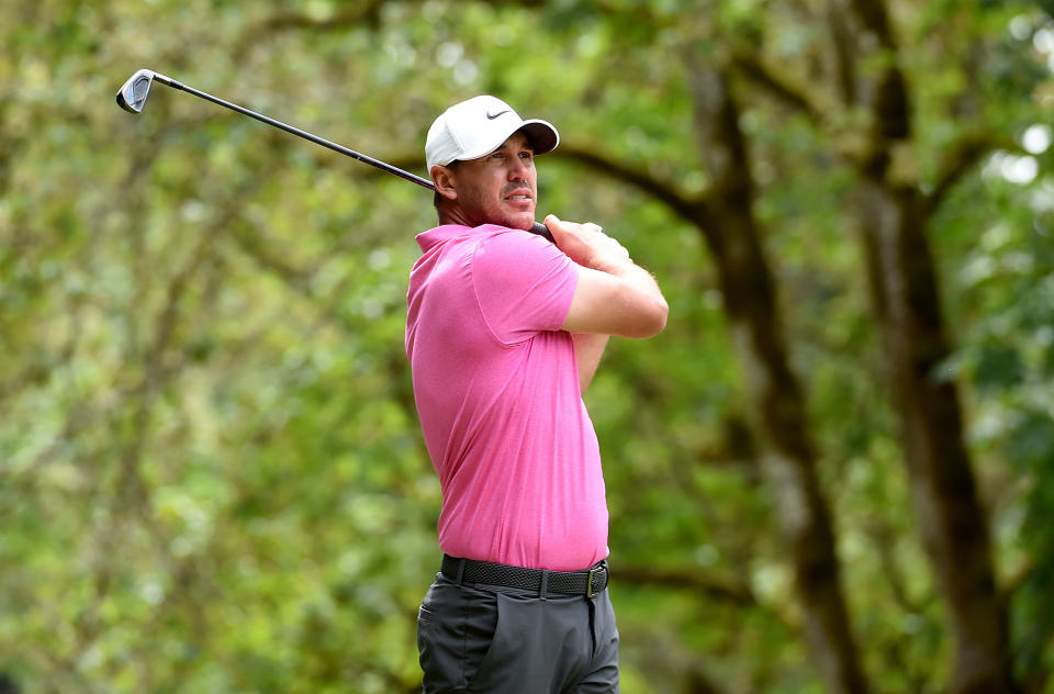 Koepka watches his iron shot whilst wearing a pink shirt