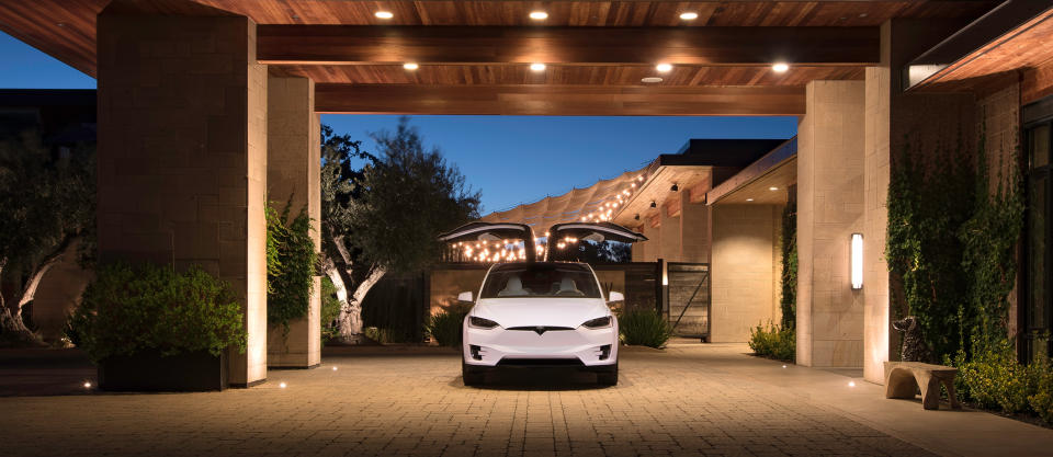 A white Model X with open falcon wing doors.