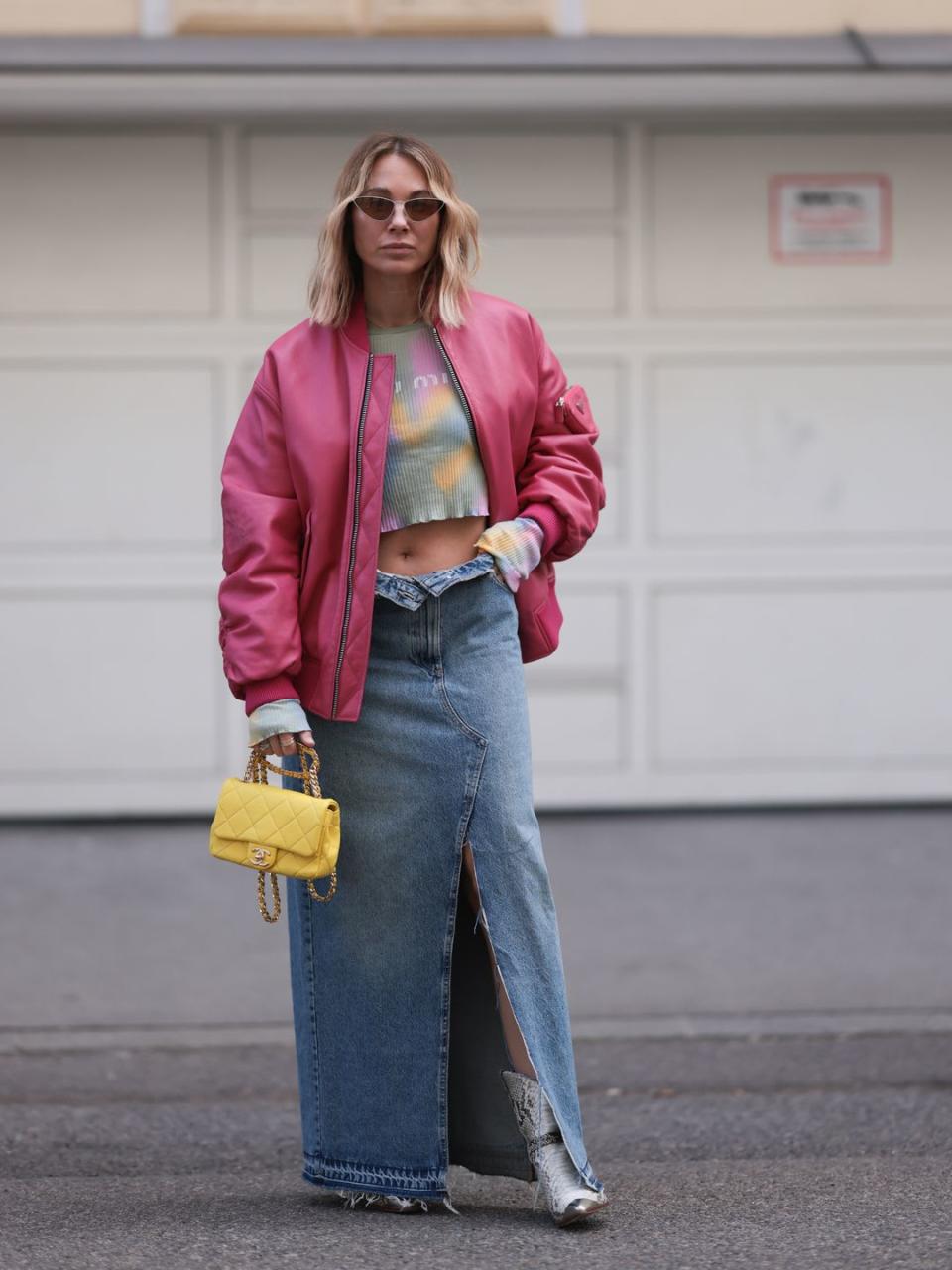 Karin Teigl seen wears snakeskin cowboy boots with a pink bomber jacket and a denim midi skirt 