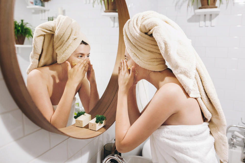 Woman applying skincare products in the mirror. Source: Getty Images